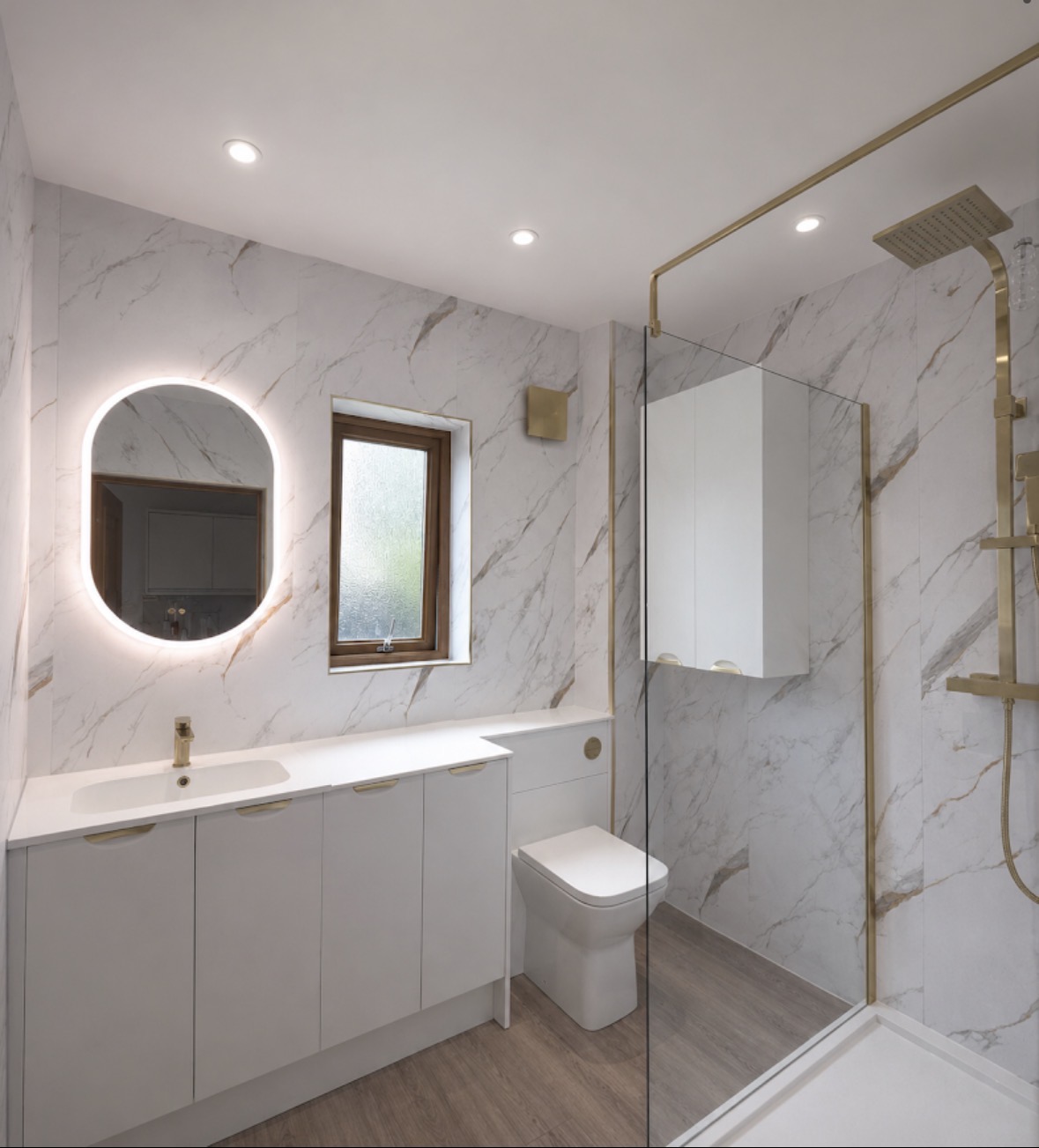 Modern white marble-effect bathroom with brushed brass shower and fitted vanity units